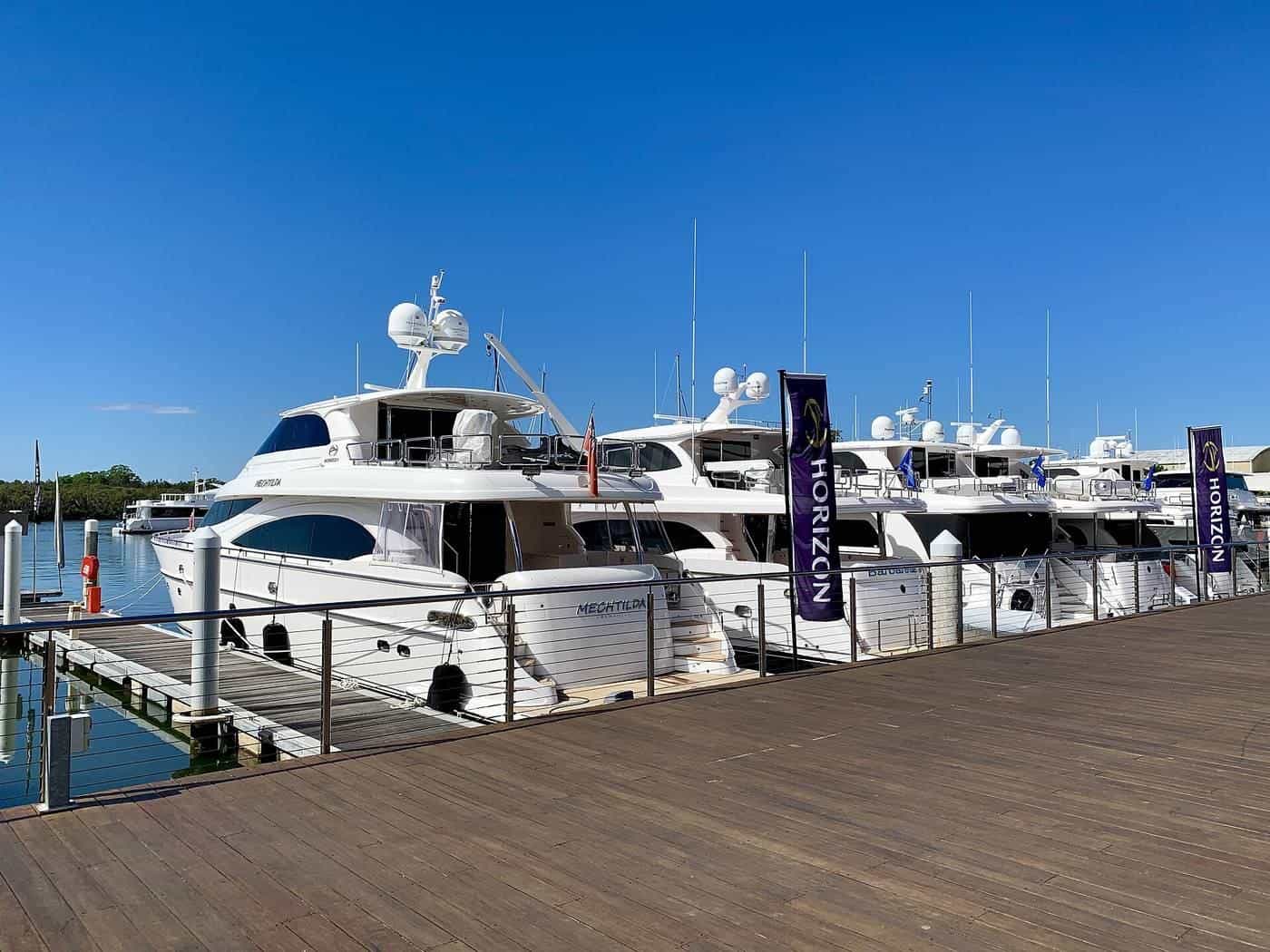 Large motor cruisers moored stern-to beside a timber marina walkway