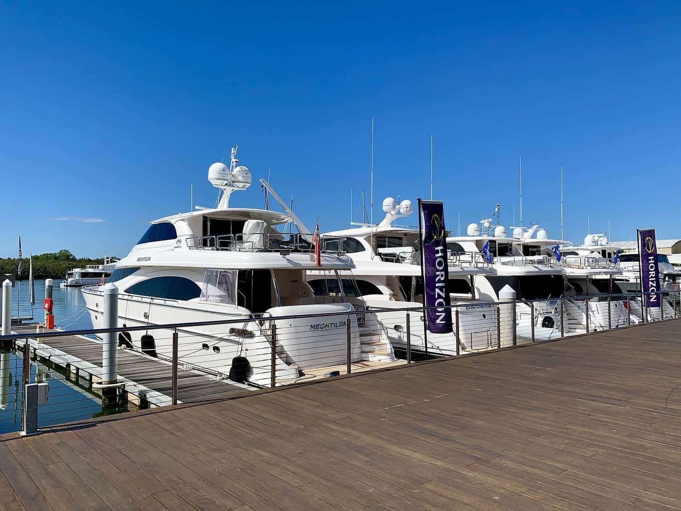 Large motor cruisers moored stern-to beside a timber marina walkway